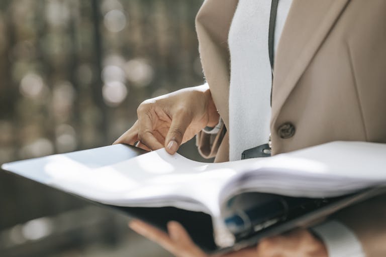 Crop faceless female entrepreneur in stylish jacket reading important documents, namely the Decree-Law 131/2024